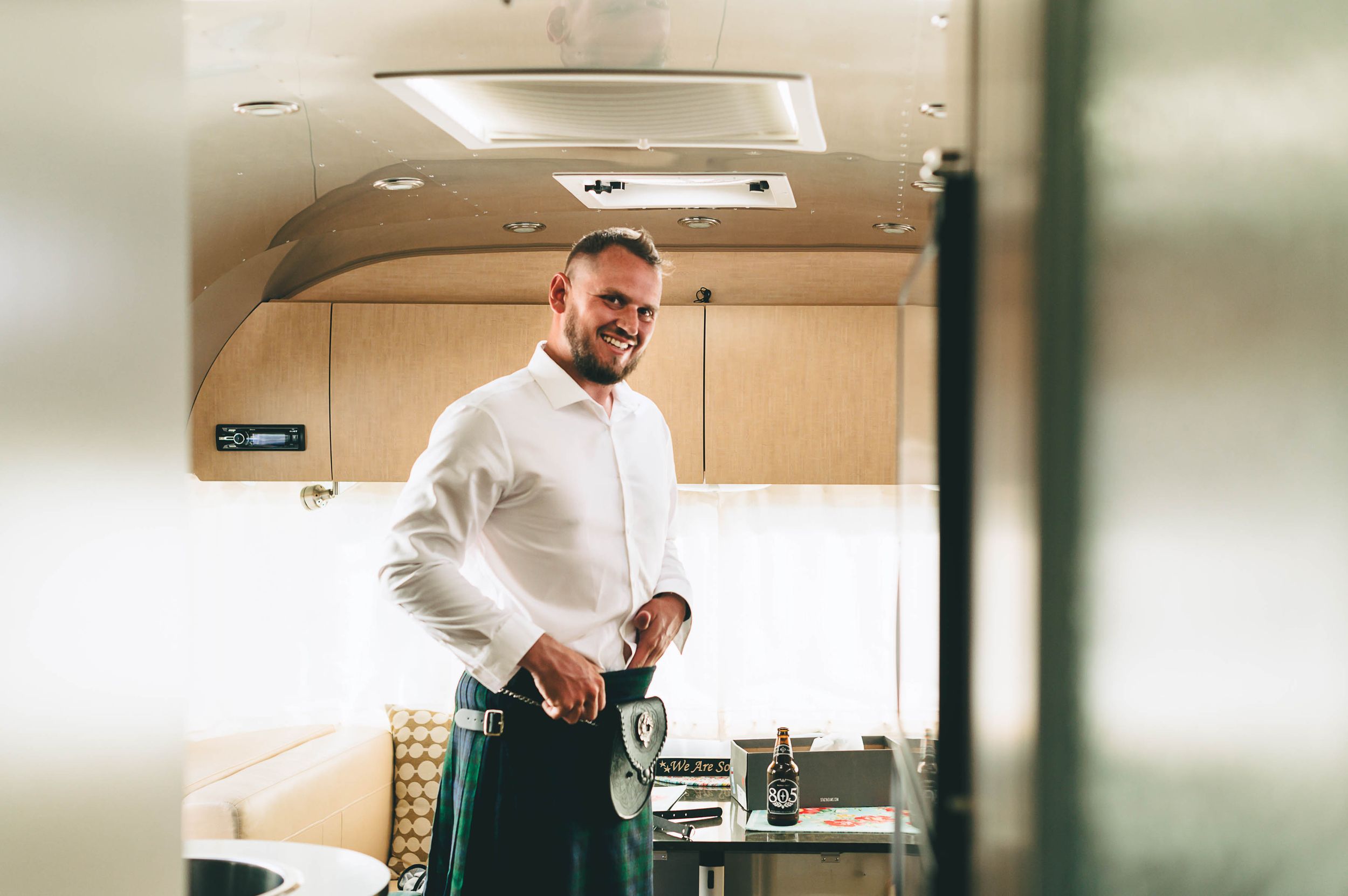 groom wearing a kilt getting ready inside an airstream trailer