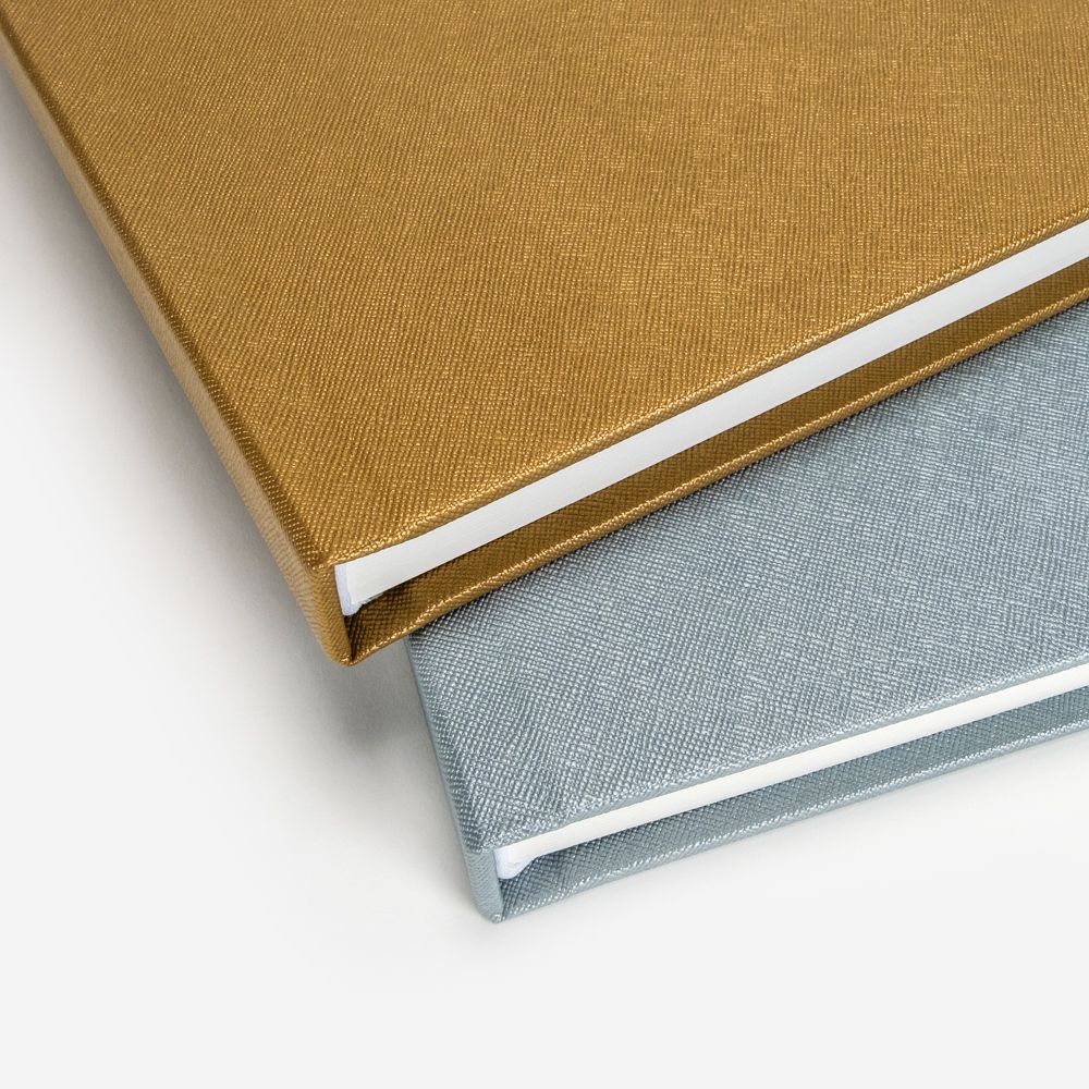 Gold and silver hardcover photo albums with textured linen covers.