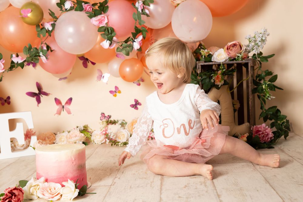 coral and flower background with butterflied and child smiling looking at cake