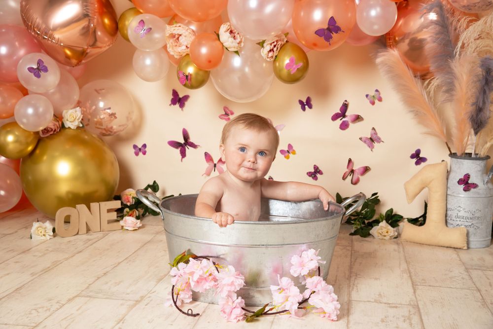 child in bath with flowers in front and the background is butterflies, flowers and coral balloons