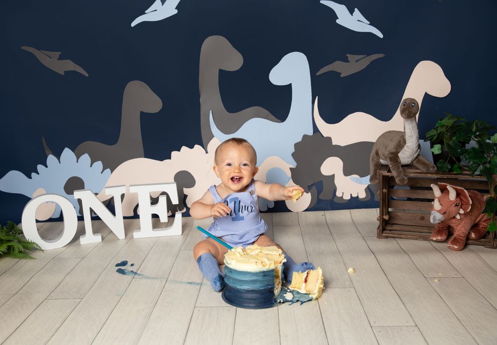 dinosaur background with a child eating catke holding a spoon
