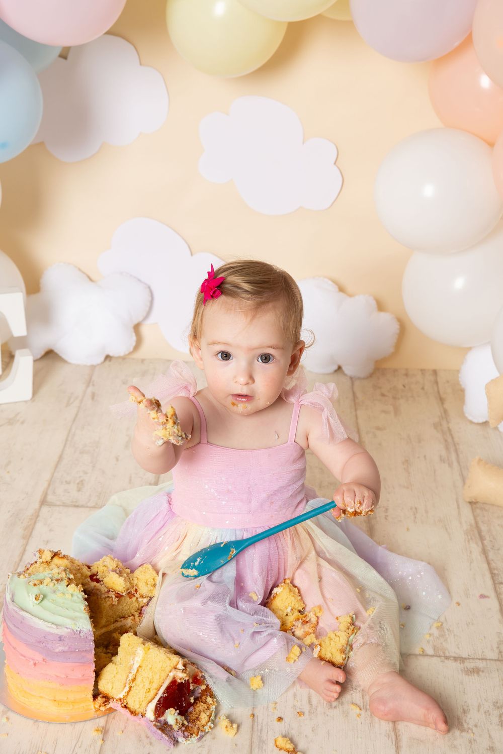 little girl looking up eating cake for her cake smash