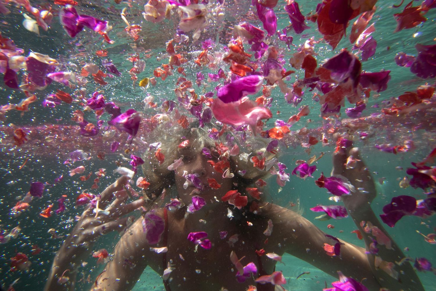 Petals floating in front of a girls face underwater