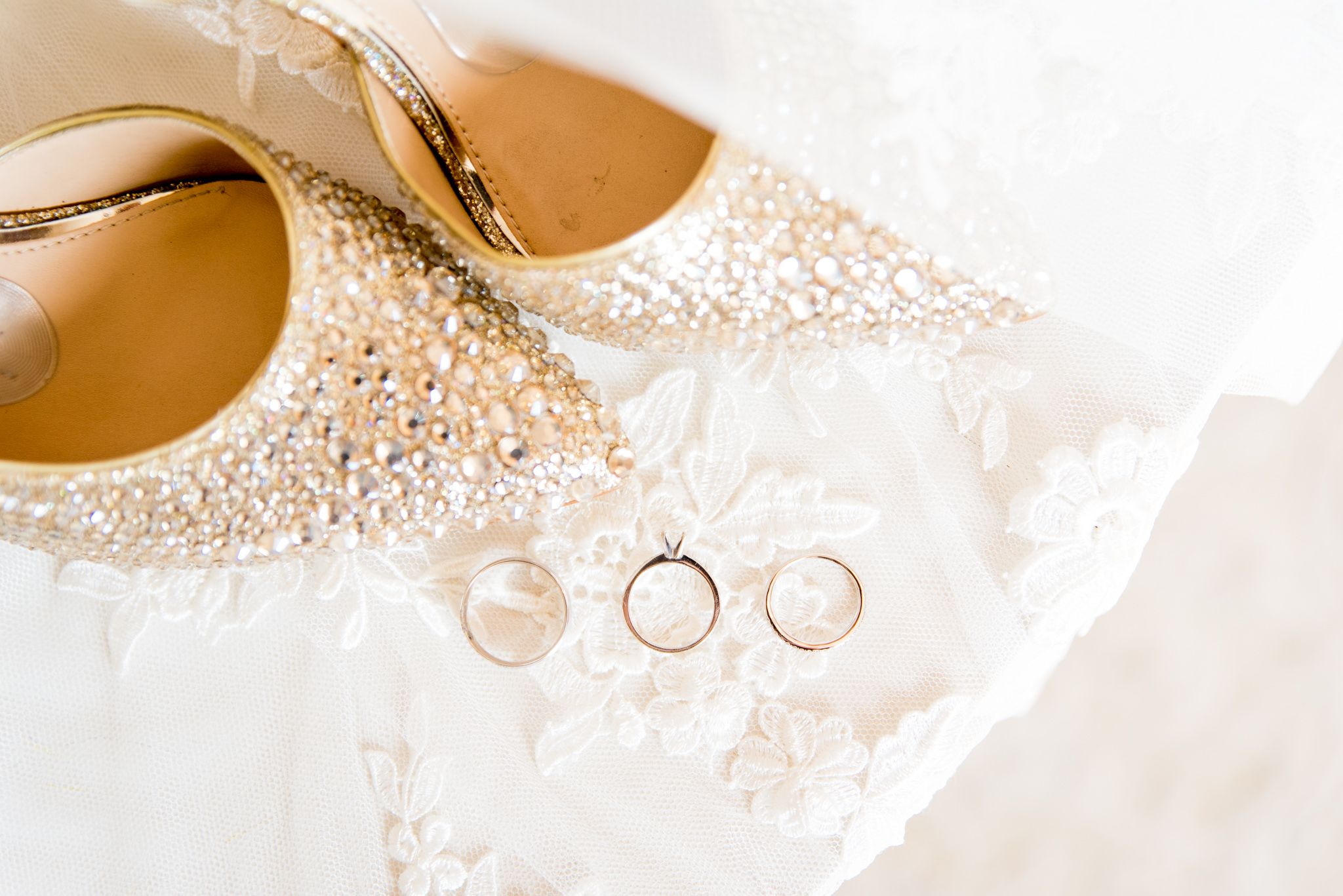sparkly rhinestone wedding heels on top of wedding veil with wedding rings