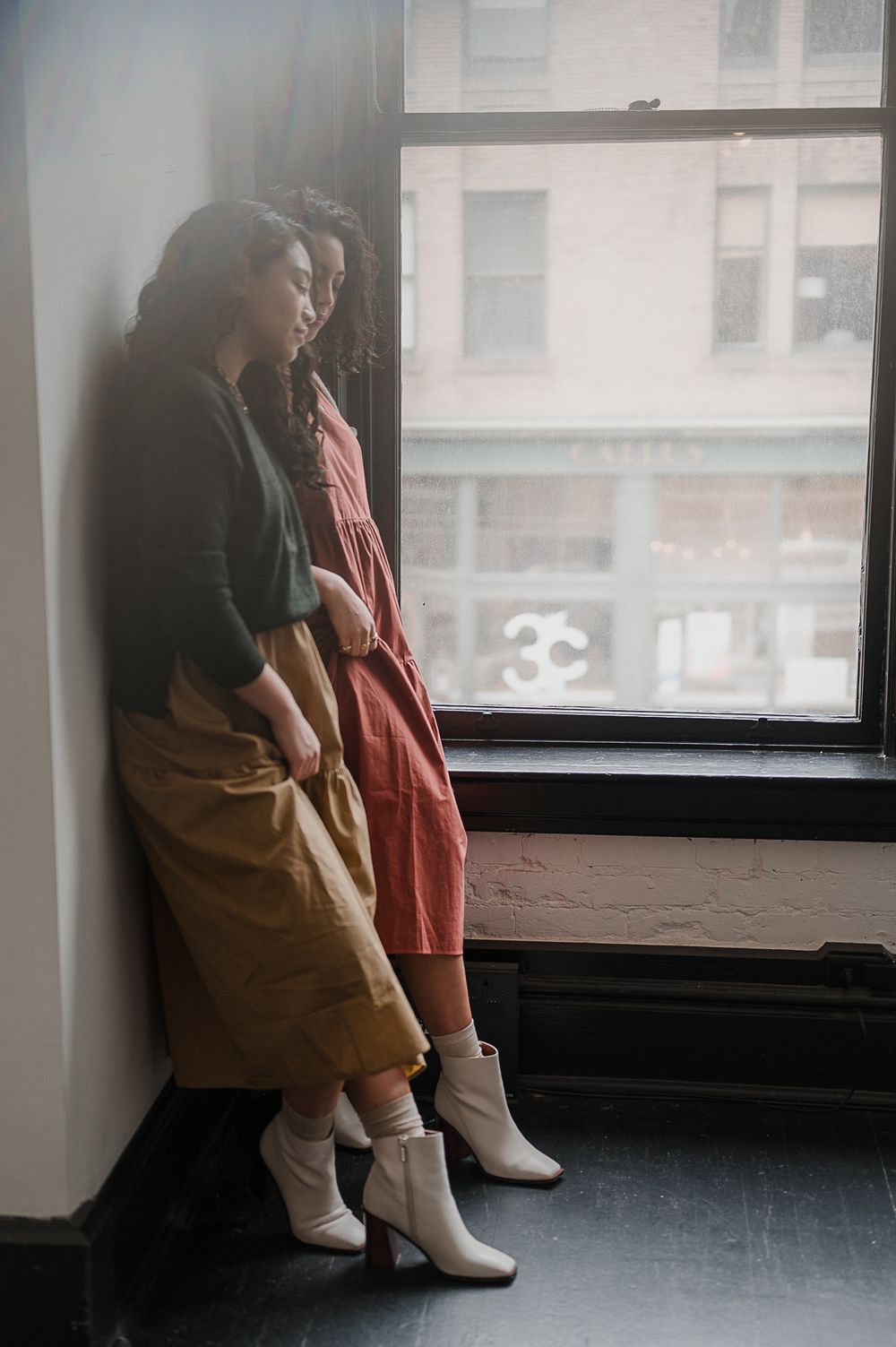 Brand campaign portrait by Tiffany Kelterer of two women leaning against a wall in Seattle fashion designers clothing