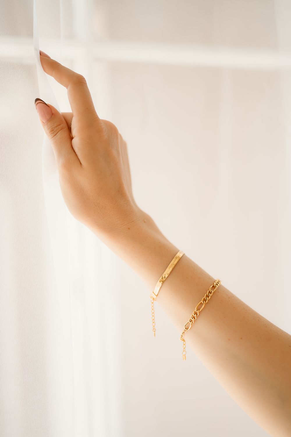 Jewelry brand photography by Tiffany Kelterer of San Diego of hand reaching up with two gold bracelets on wrist