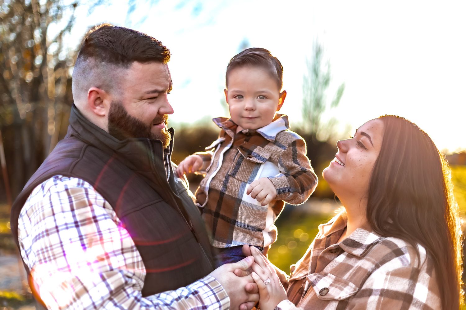Family shares joyful moment together in matching plaid outfits during outdoor photoshoot.