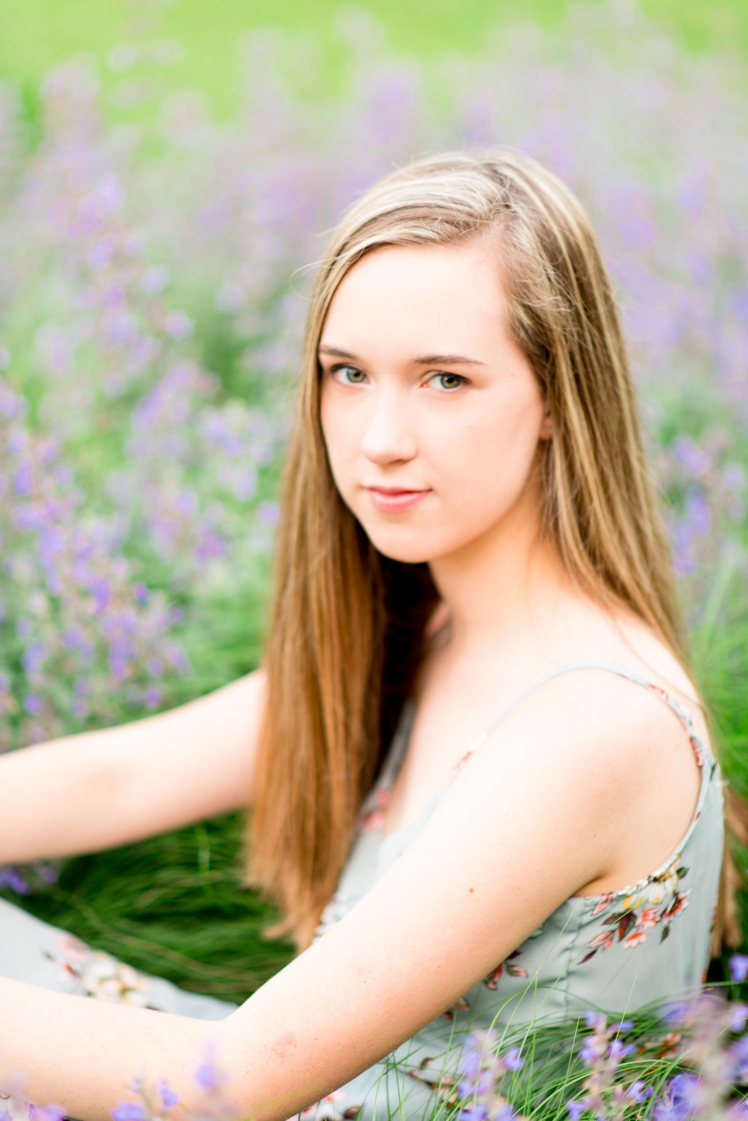 young woman with green eyes sits in a field of lavender in Chicago Lurie Garden for senior pictures