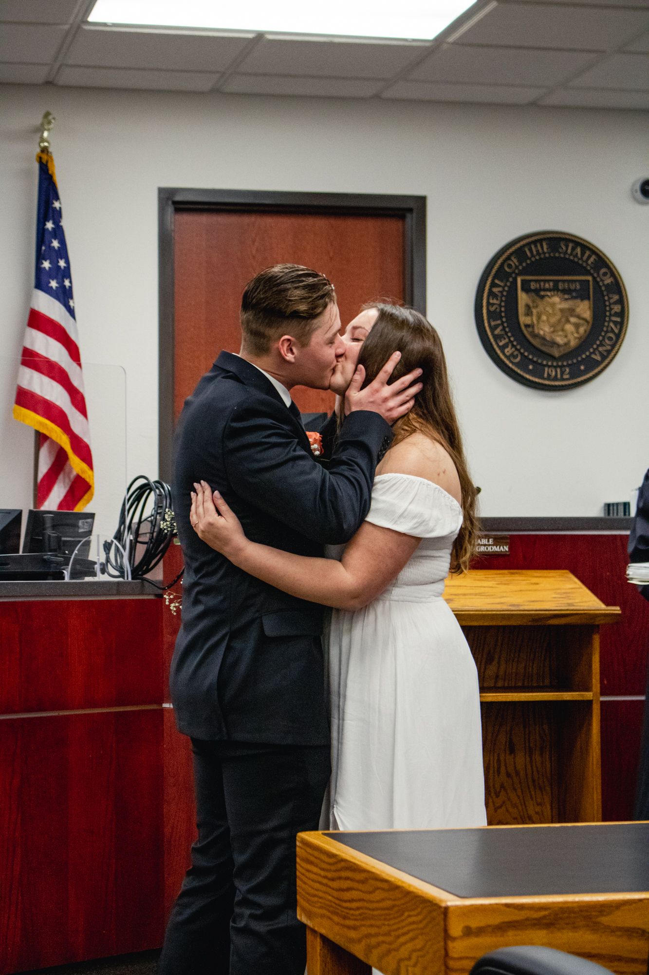 Indoor courthouse wedding ceremony with American flag and official seal visible.