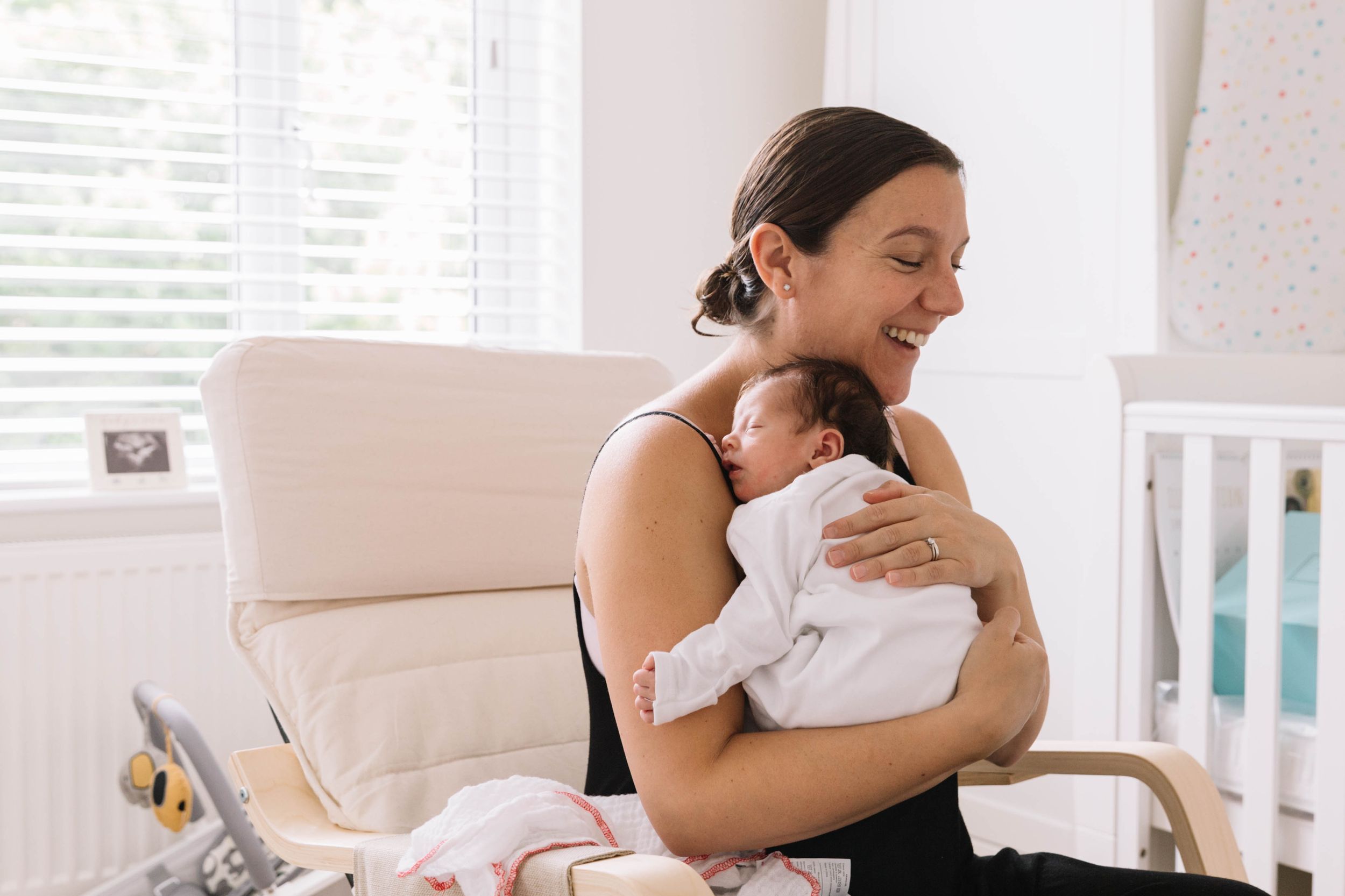mum smiling holding newborn baby daughter