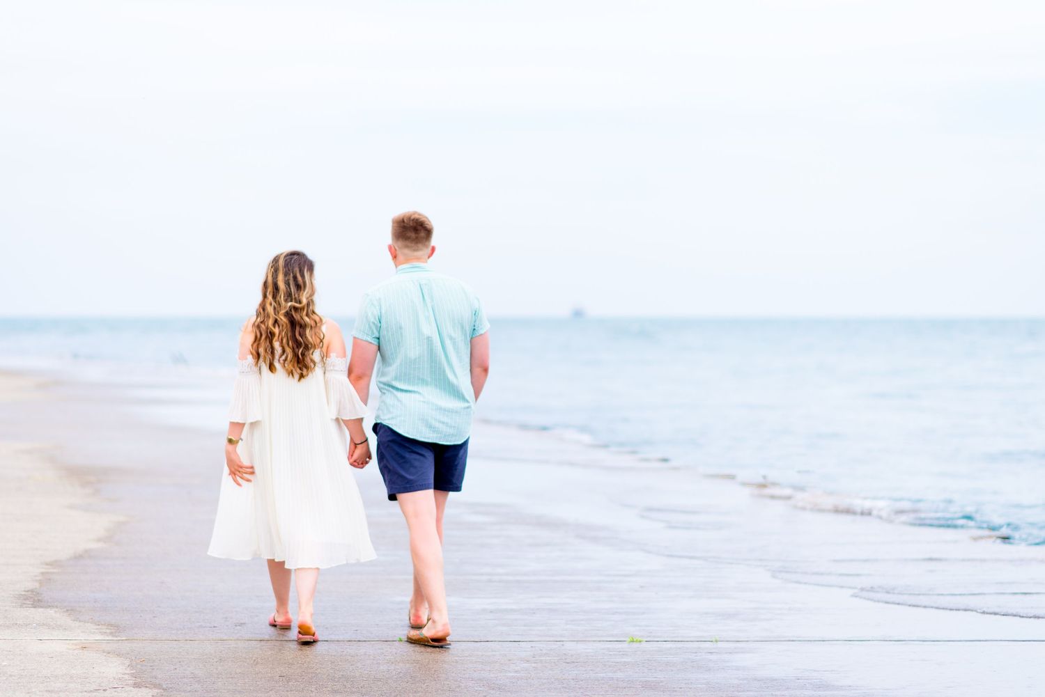 engaged couple holding hands walking away along Lake Michigan at Montrose Harbor for sunrise engagement pictures