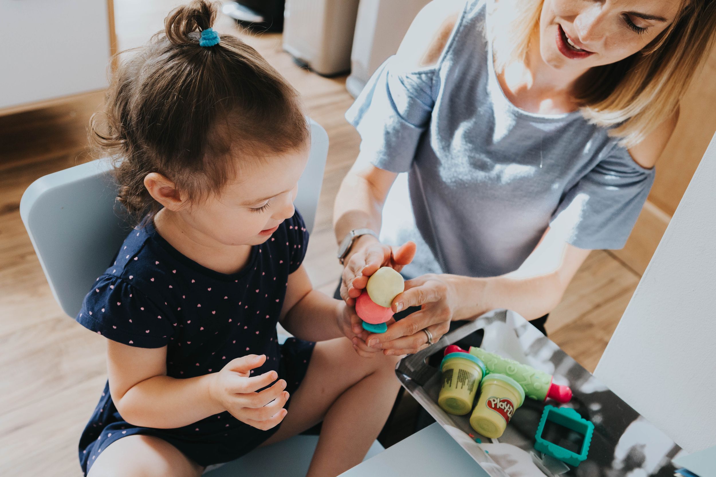girl in navy dress playing play doh with mum