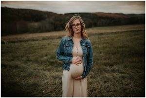 pregnant mom in jean jacket looking right at camera smiling