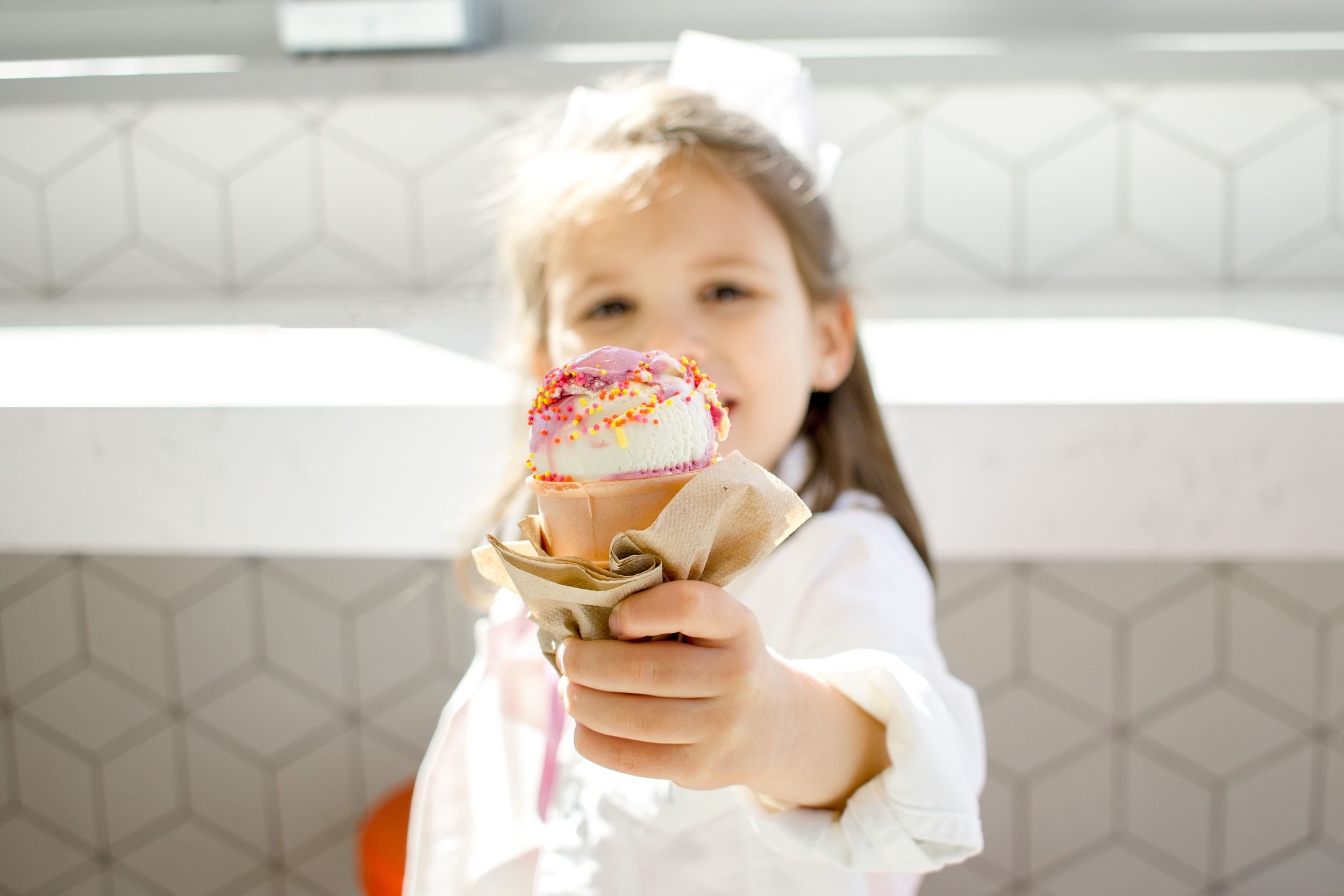A little girl holding out her ice cream cone inside Jen's Ice Creams South End
