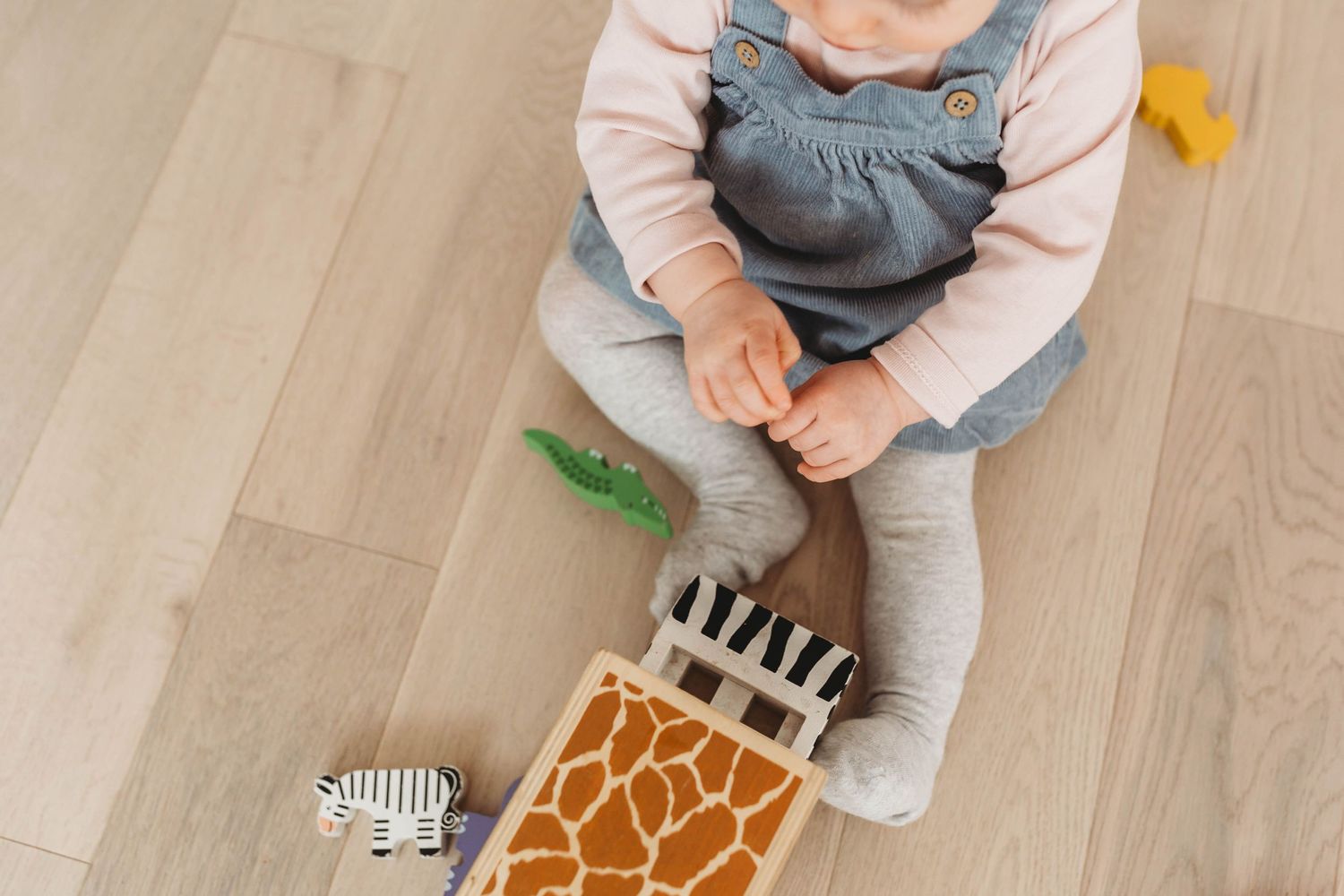 little baby girl sitting on the floor playing with wooden toy