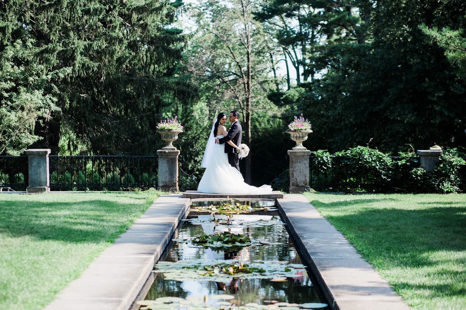 Bride and groom reflected in pool at Skylands Manor