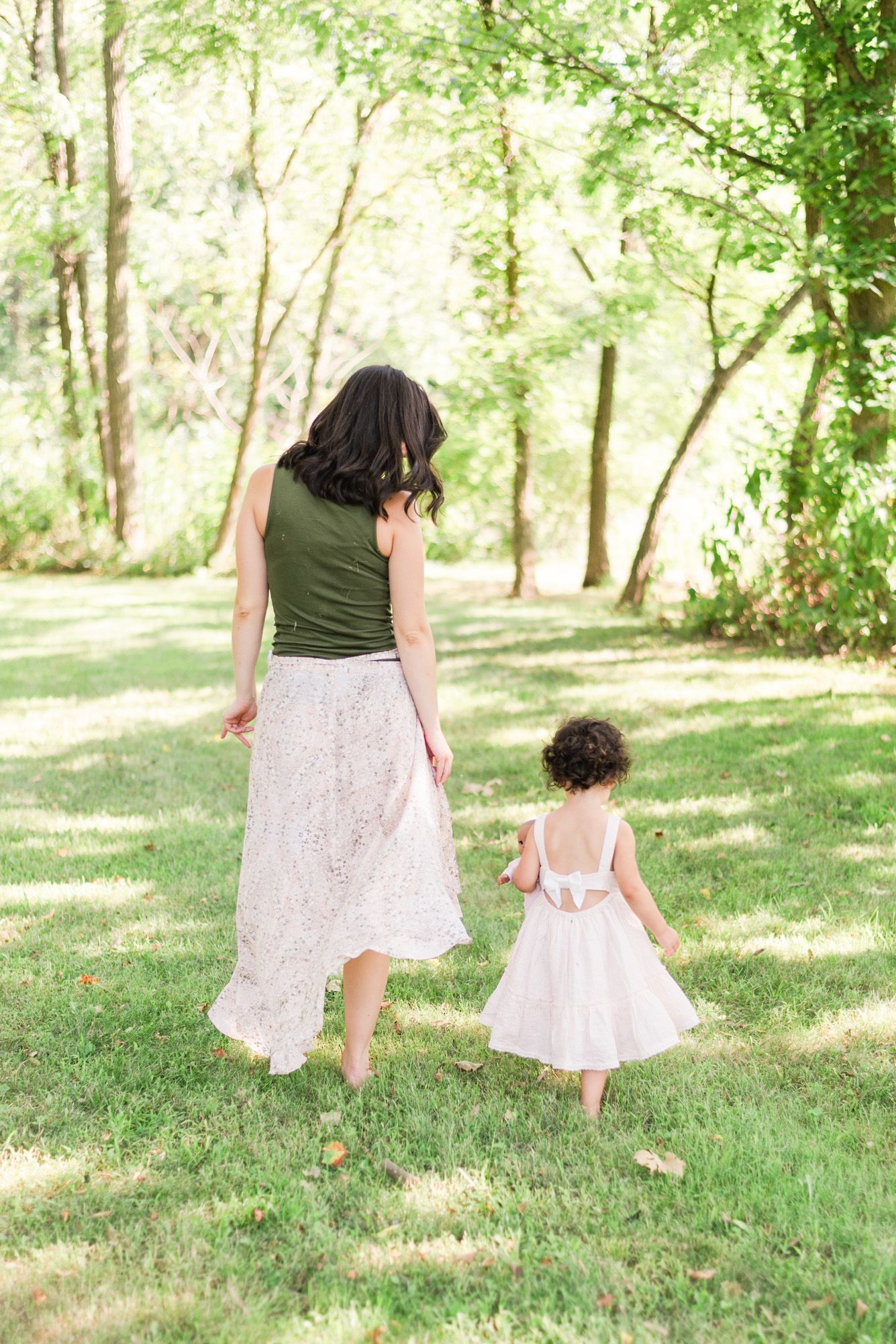 Mom and toddler daughter walking through woods in sunlight at Emmerling Park in Cheswick Pennsylvania
