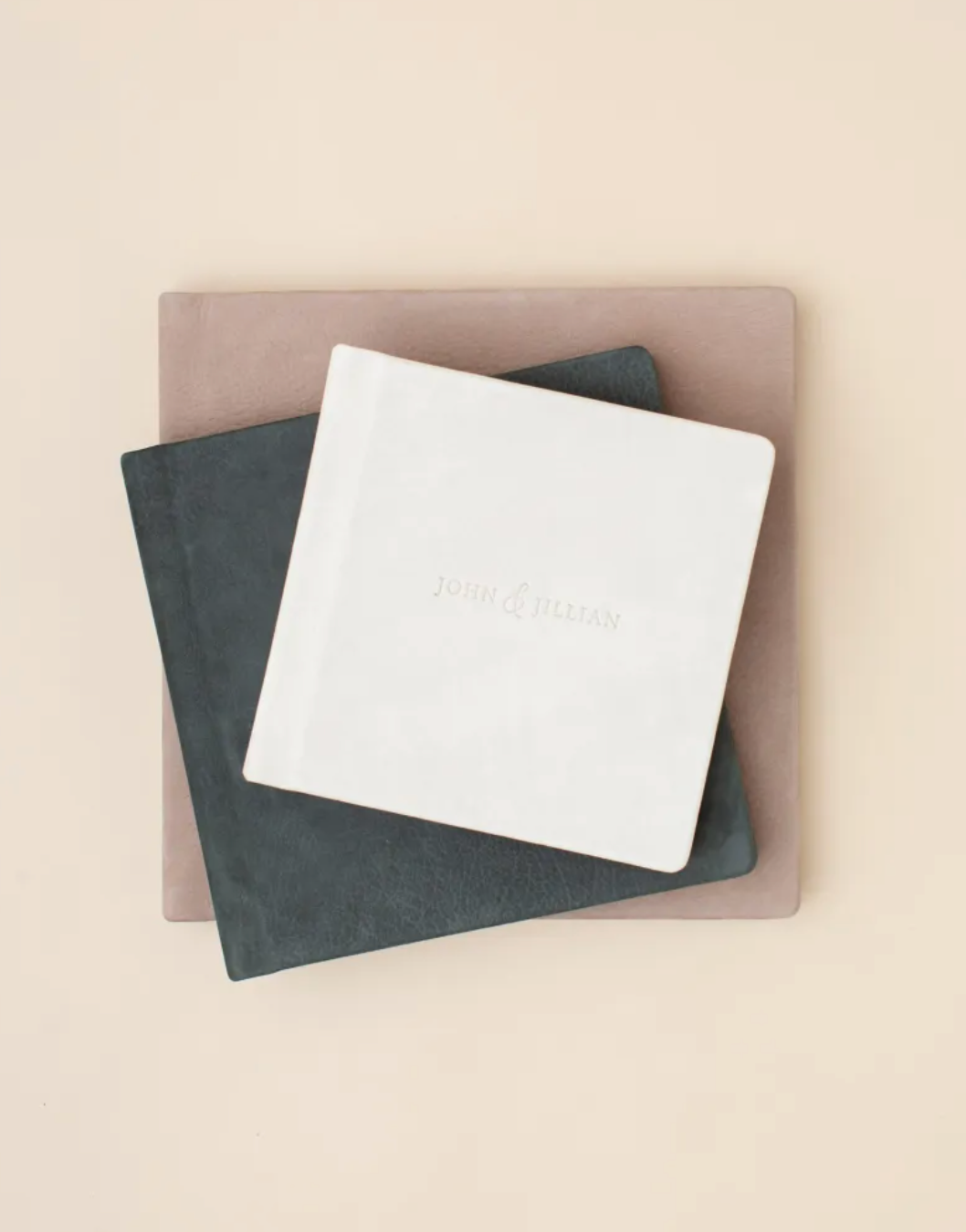 Stack of three luxury photo albums in white, grey and blush tones.
