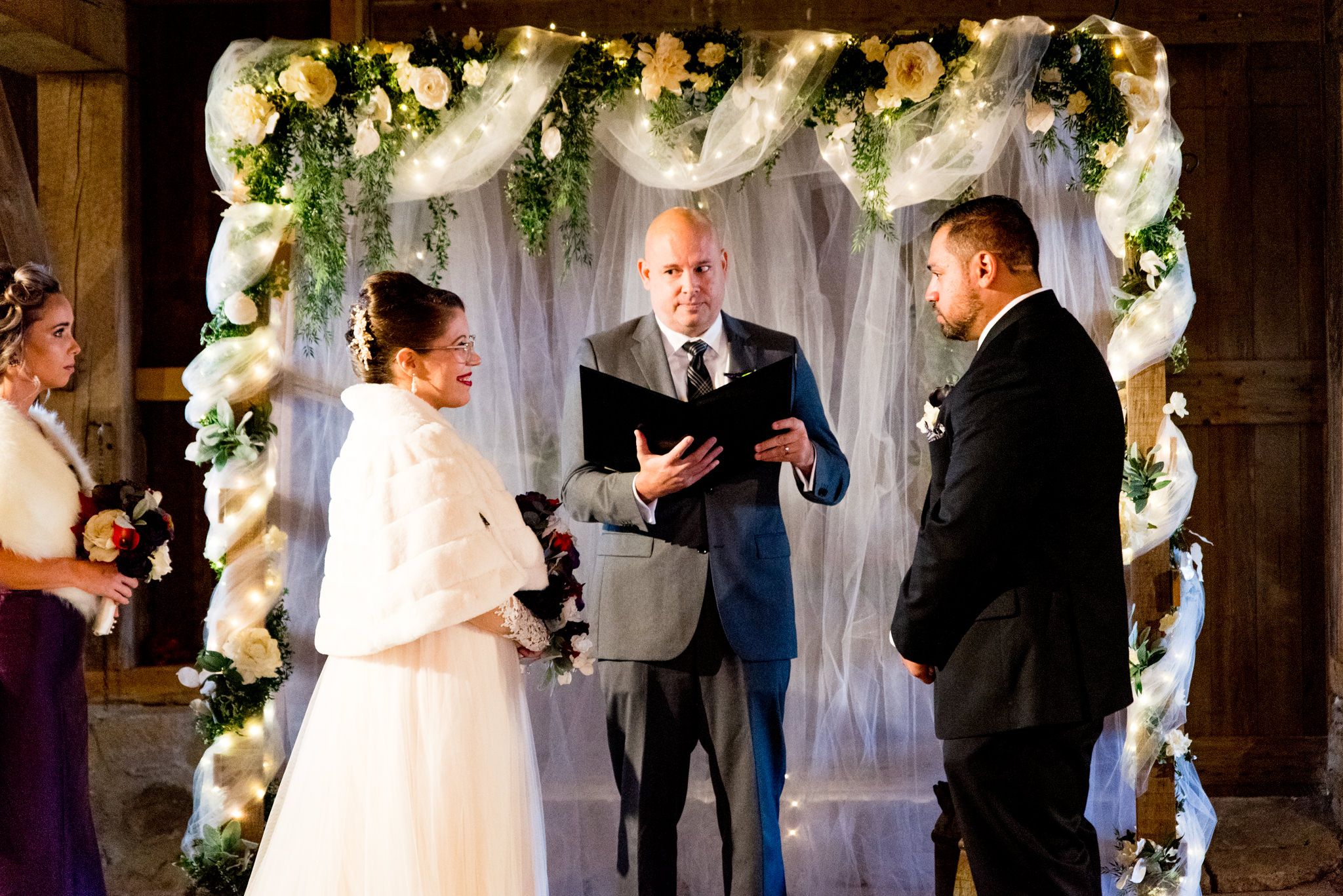 bride smiles at groom at wedding later in barn wedding
