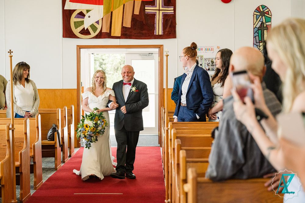Traditional church wedding processional on red carpet aisle with floral bouquet.
