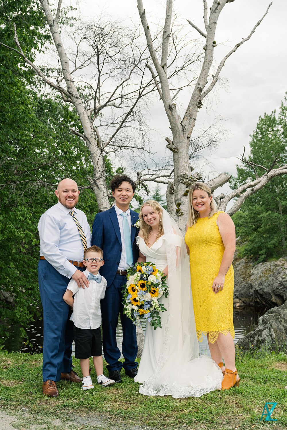 Wedding party poses together under white birch trees in natural outdoor setting.