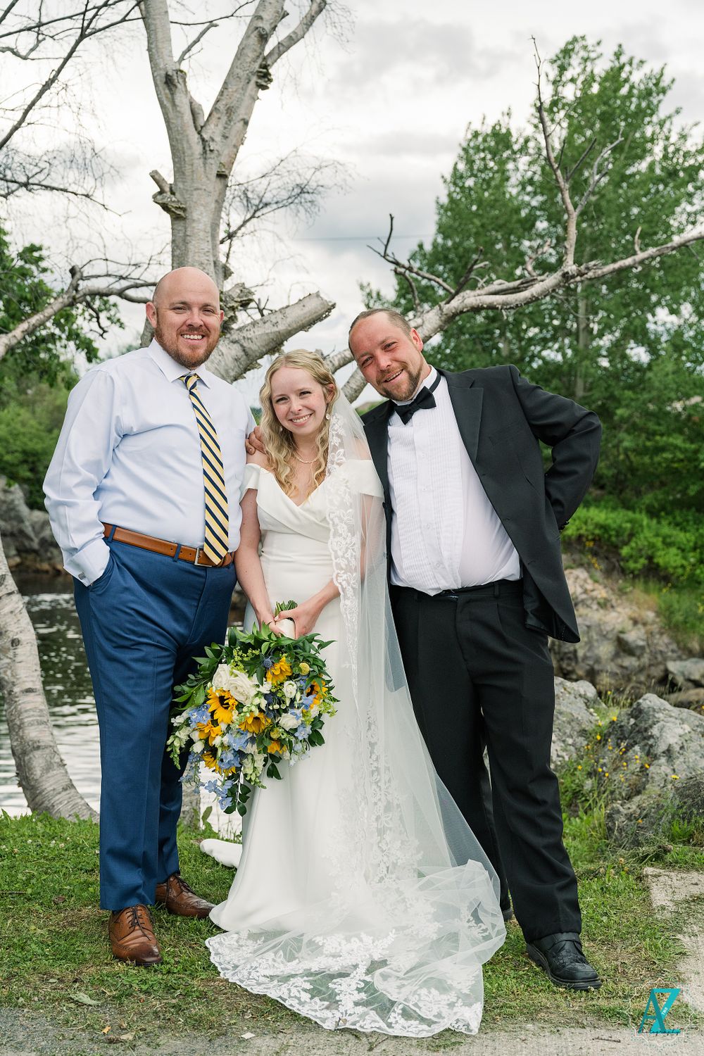 Wedding photo with three people laughing together outdoors by white birch tree.