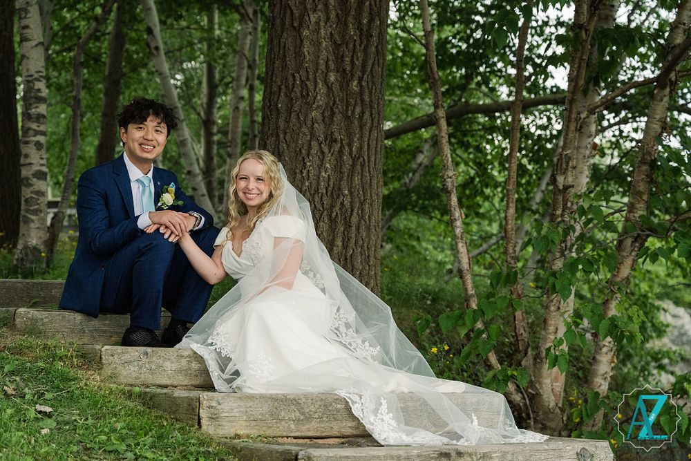 Couple sitting on wooden steps in wooded area sharing joyful moment.