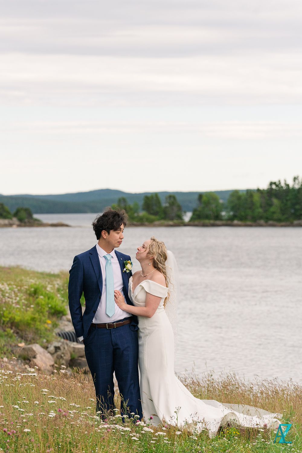 A tender moment between newlyweds on a coastal hillside with water views.