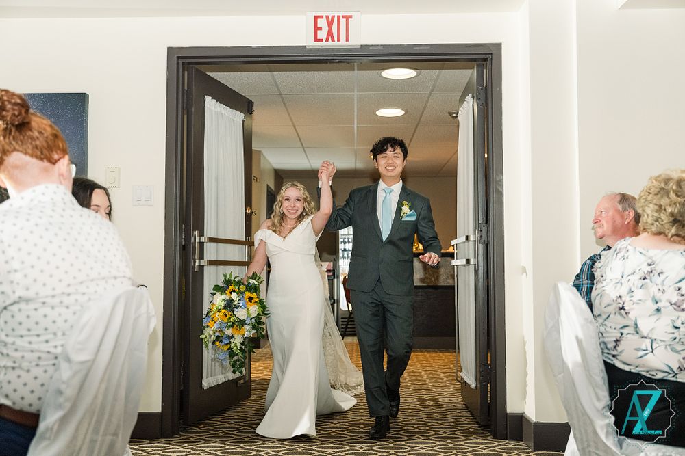A joyful wedding entrance through double doors as guests watch from their seats.