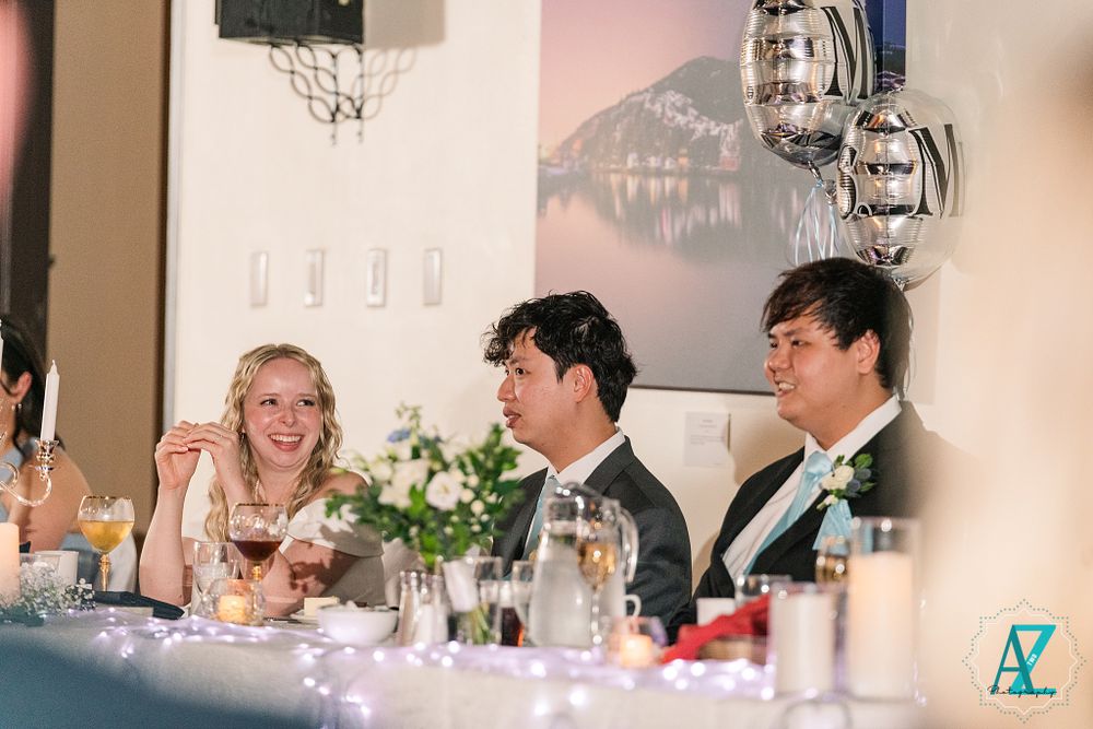 Wedding reception scene with guests enjoying drinks and conversation at the head table.