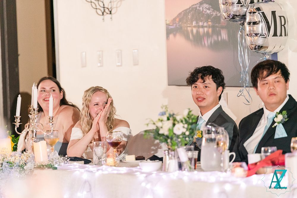 Candid moment of wedding party members laughing together at the reception head table.