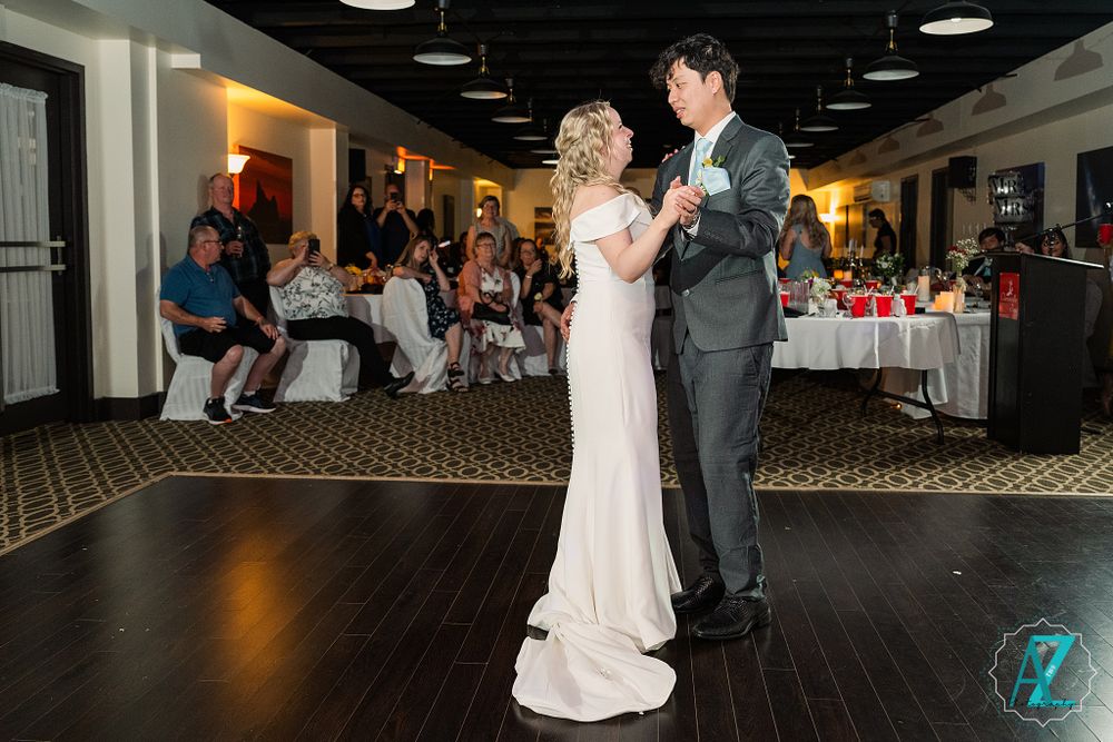 First dance of newlyweds on a dark wooden dance floor at their reception.