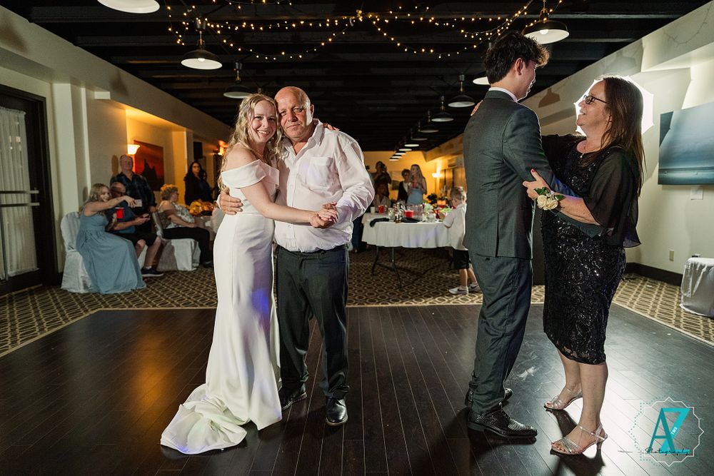 Couples dancing together on a wooden floor at an evening wedding reception.
