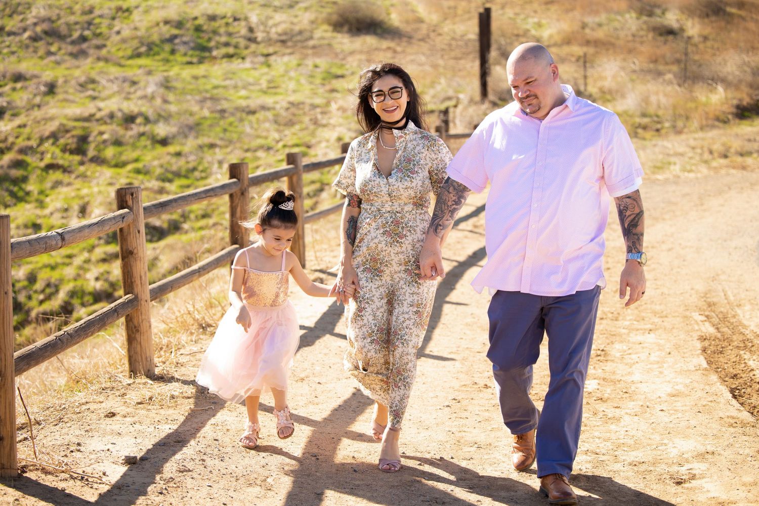 family of three holding hands while walking