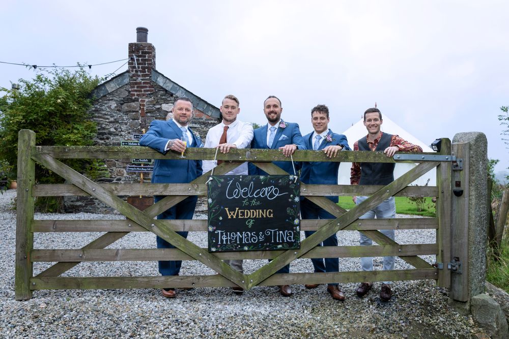 groom and groomsmen posed for wedding photo by gate. Rustic country barn wedding