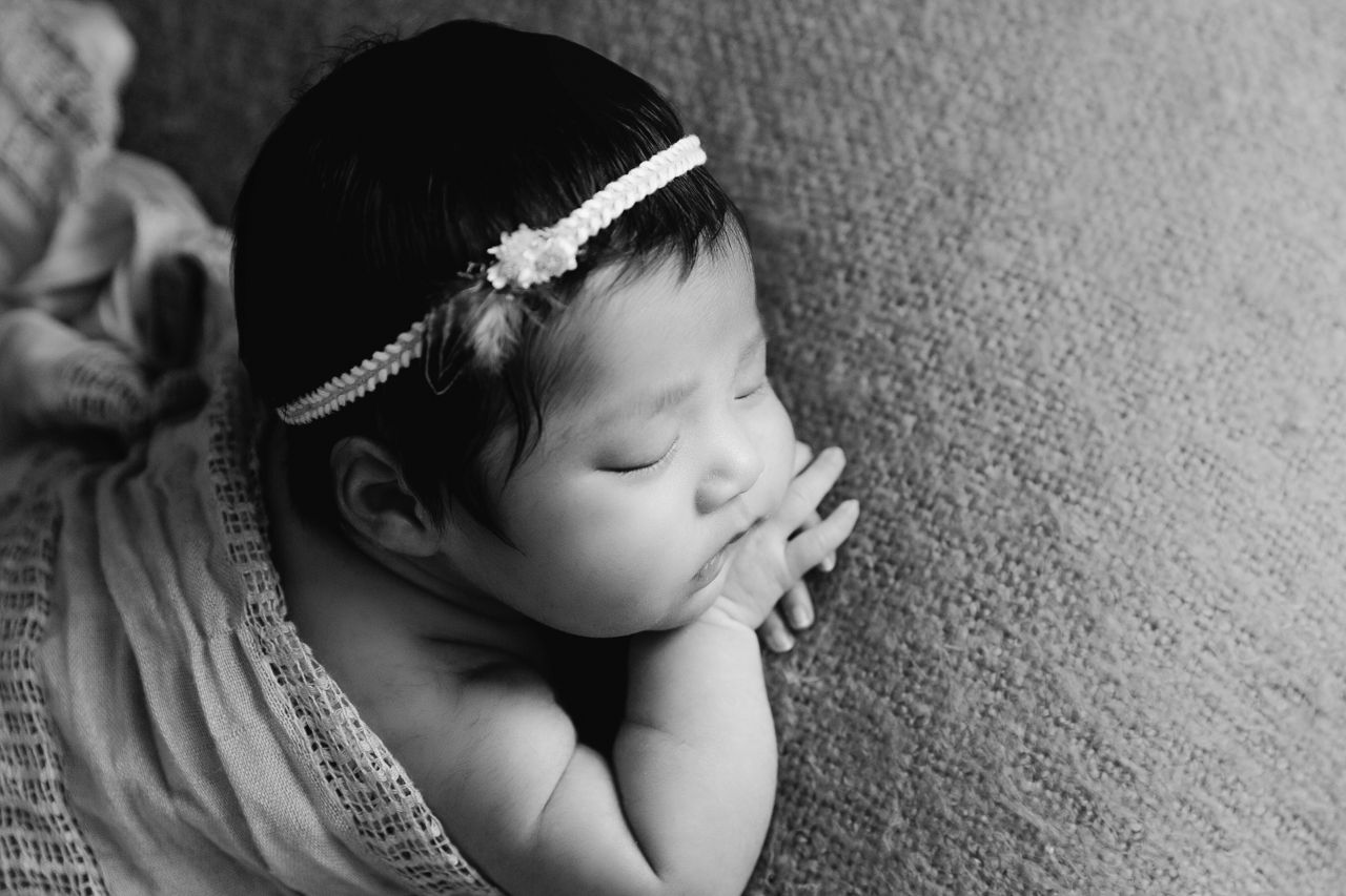 close up profile of infant in black and white with feather boho headband