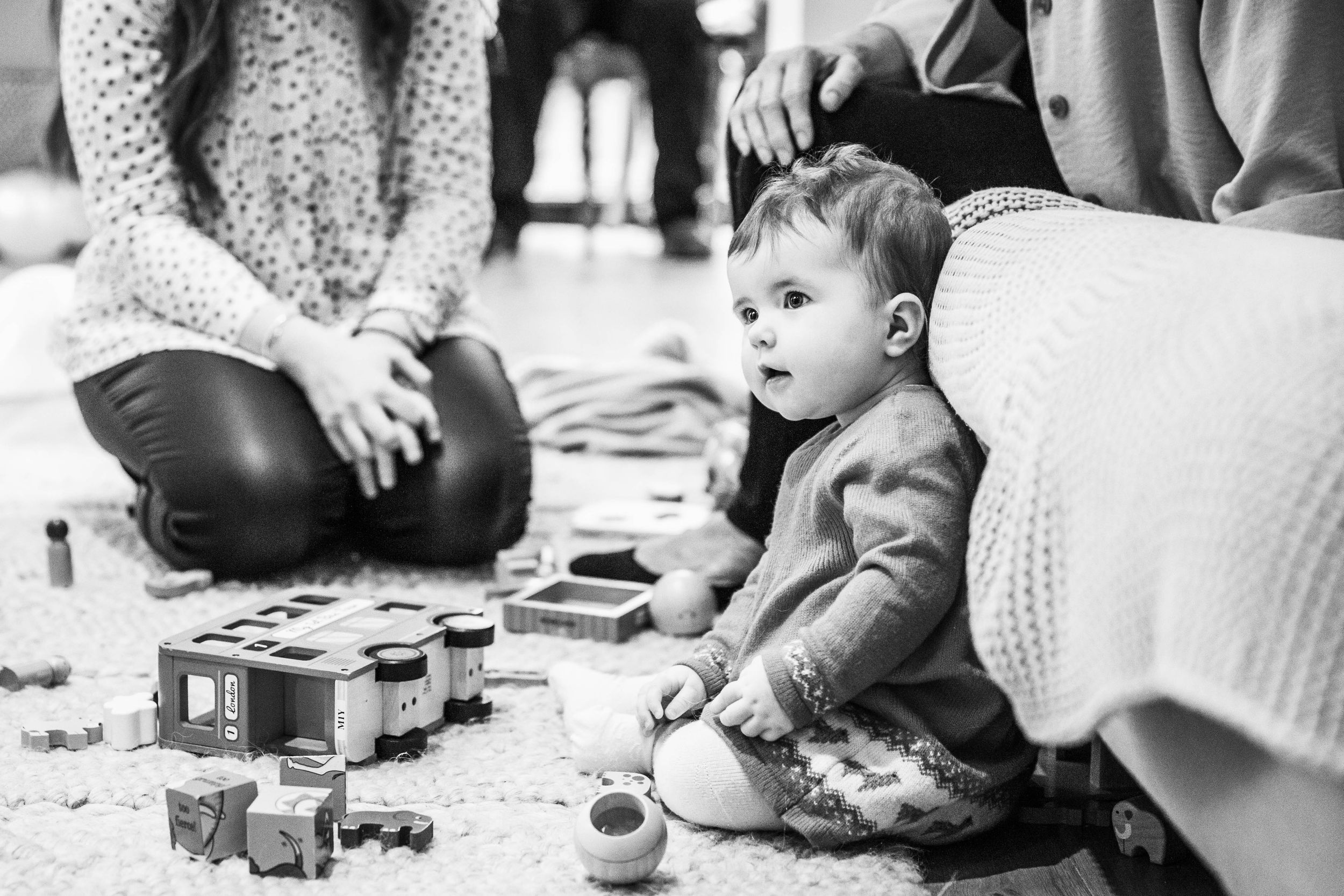 little baby girl sitting on floor playing with toys at birthday party