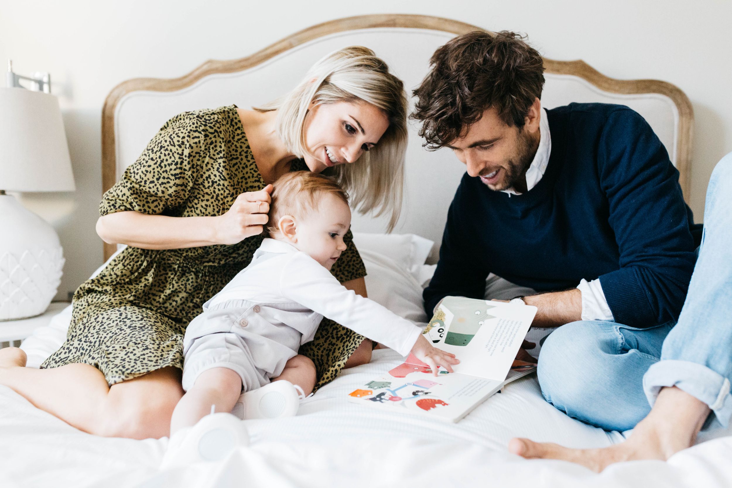 brentwood family photographer mum gently caressing toddler son head while sitting on bed with dad