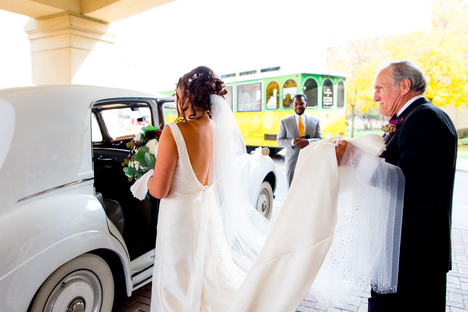 dad holds his daughters wedding veil as they enter a bentley in chicago