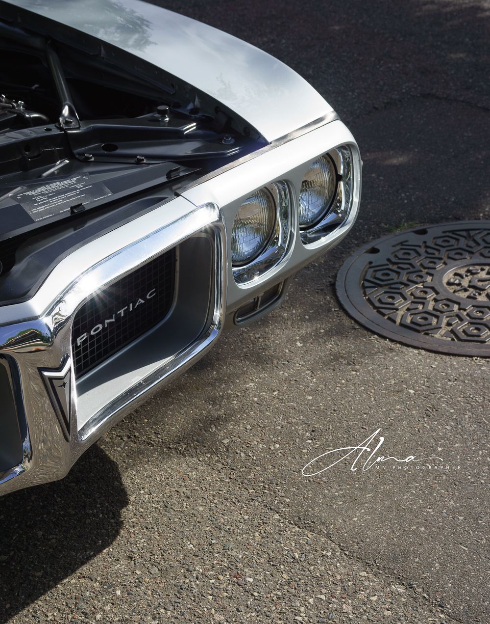Close-up of classic Pontiac chrome headlight and grille design.