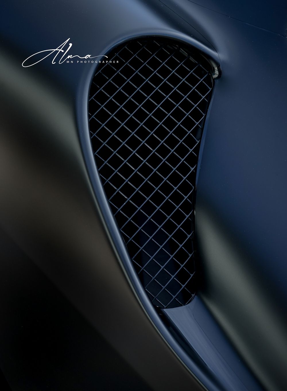 Detailed shot of a luxury car's dark mesh grille pattern.