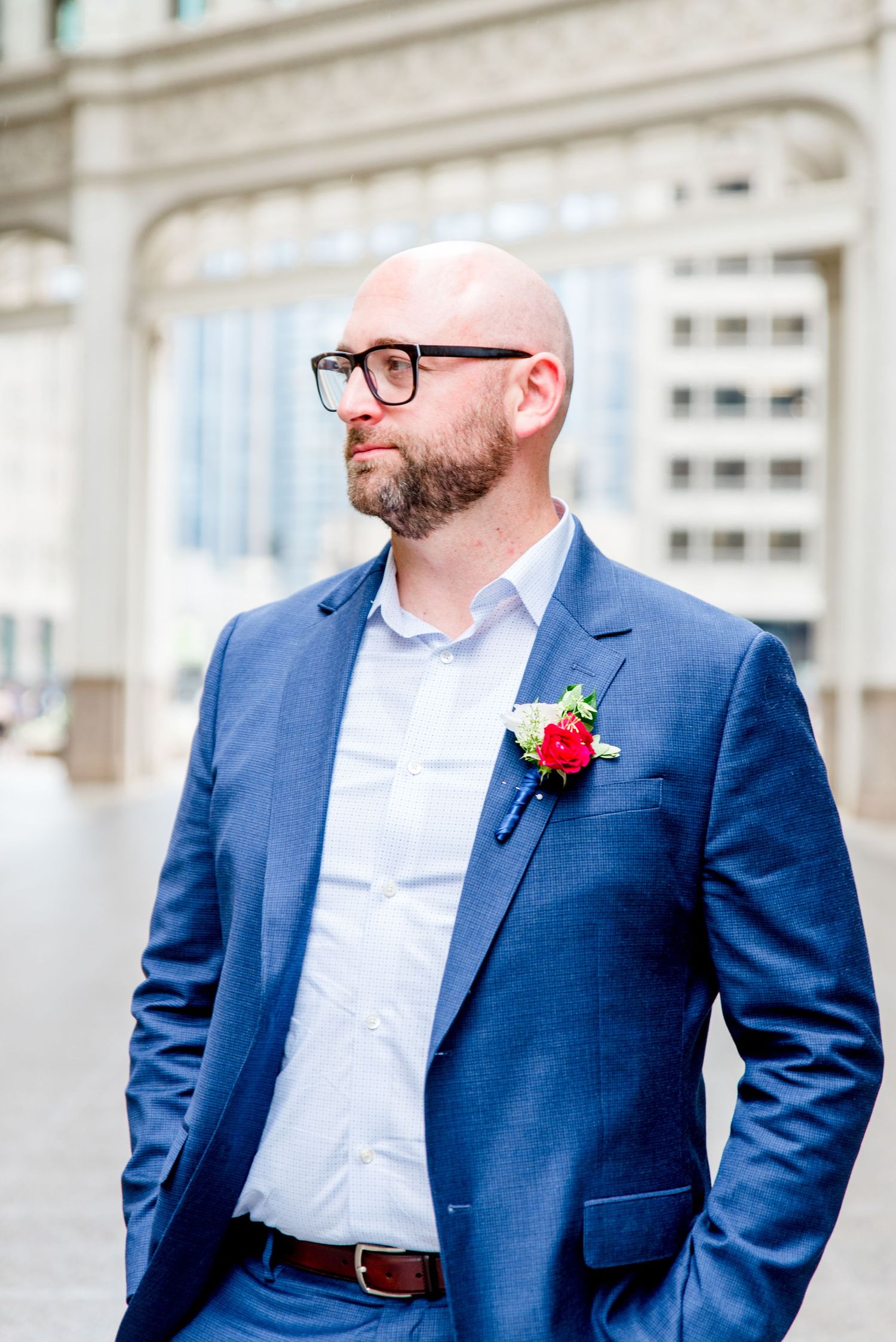 man in navy suit and glasses standing under Wrigley Building Chicago
