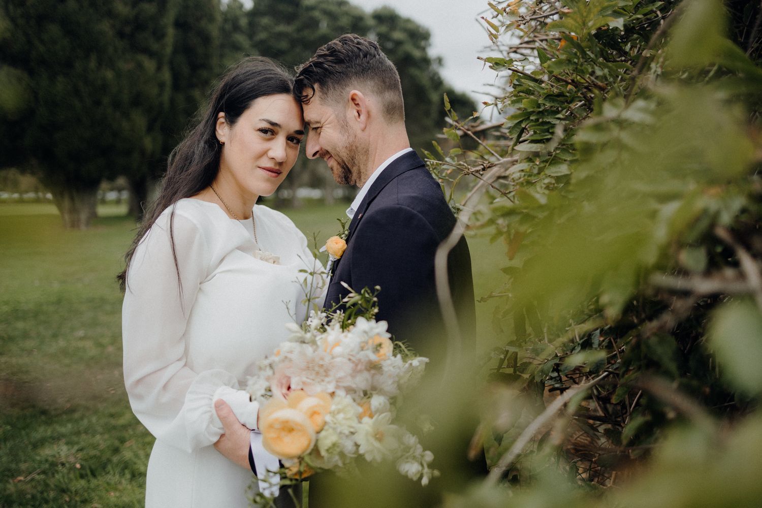 Romantic moment captured through greenery in a garden setting.