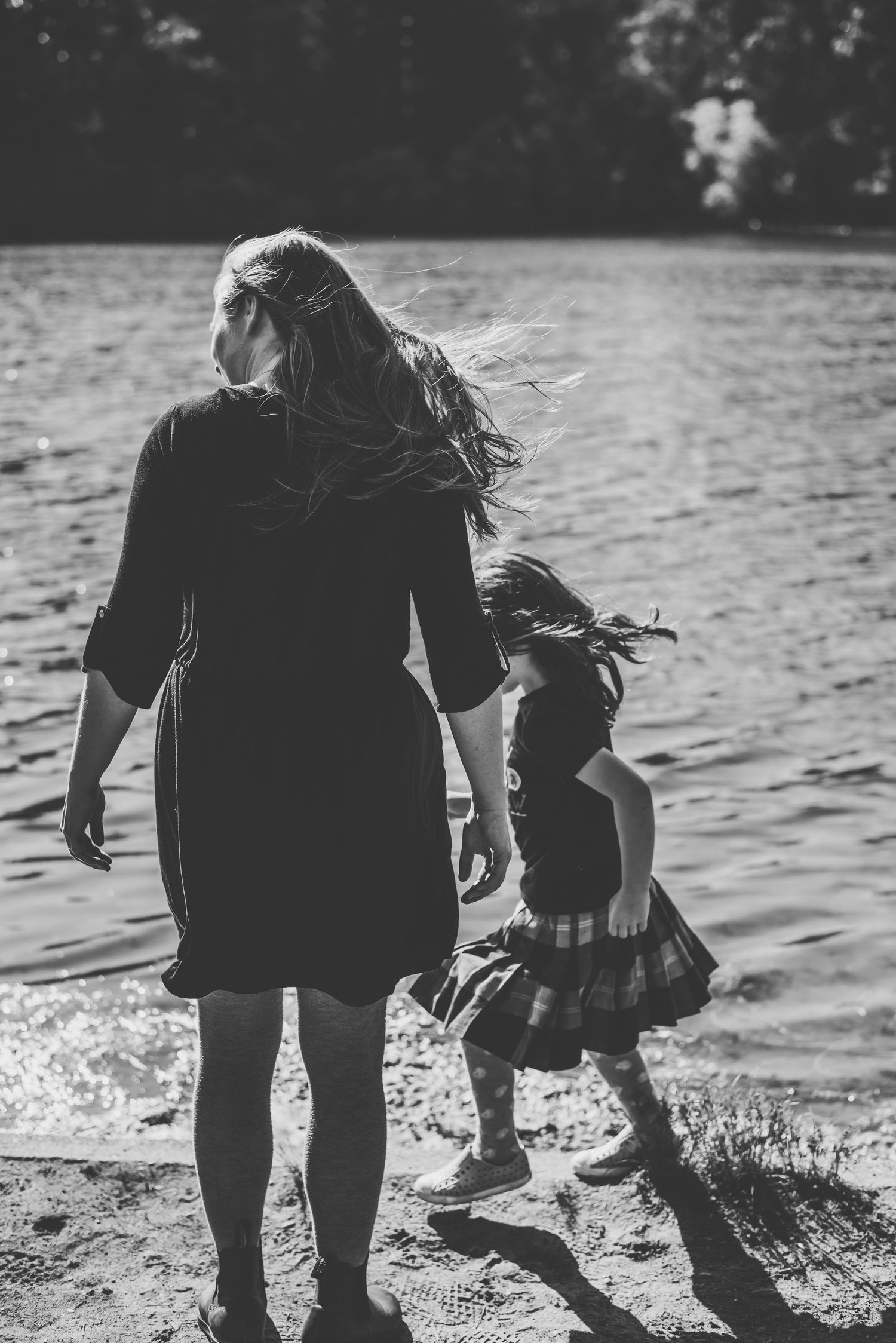 Mother and daughter playing at the edge of a lake in black and white.
