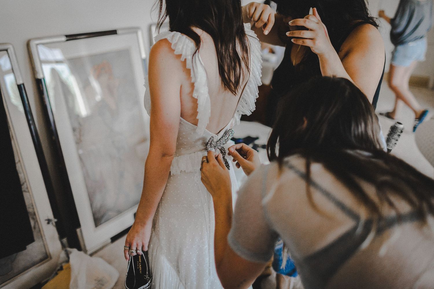finishing the bow on back of wedding dress for bride