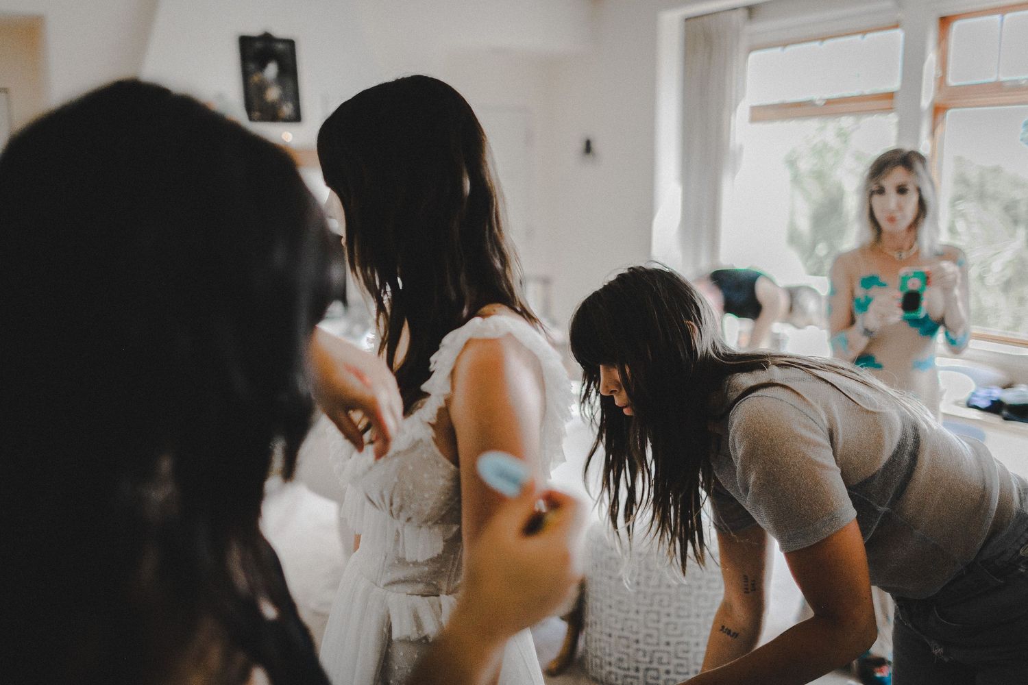 bridal party helping put on details for wedding dress on bride