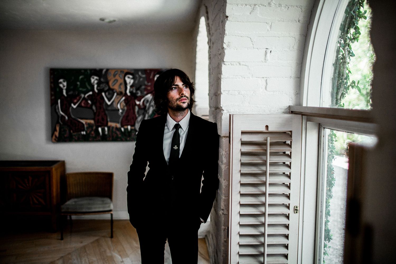 groom standing next to window at residence looking towards window