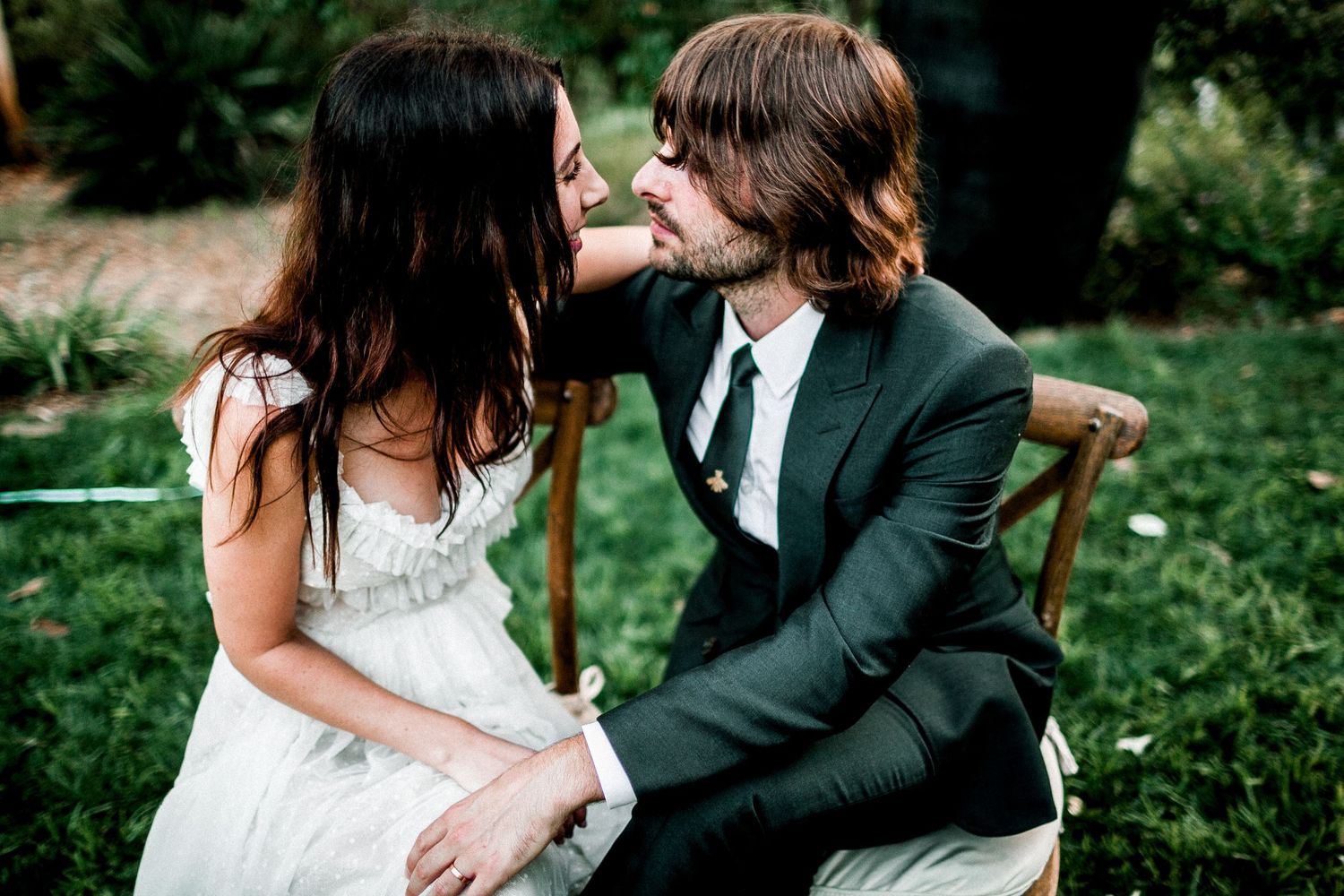 bride and groom sitting on chairs in lawn looking at each other
