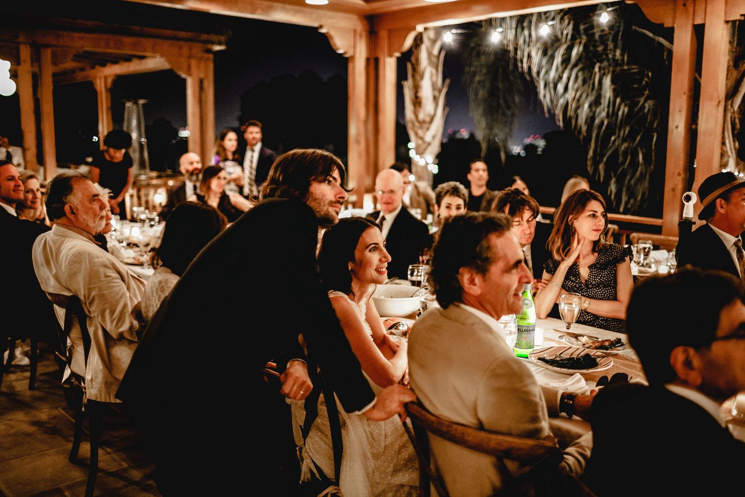 bride and groom listening to best man speech at reception at night