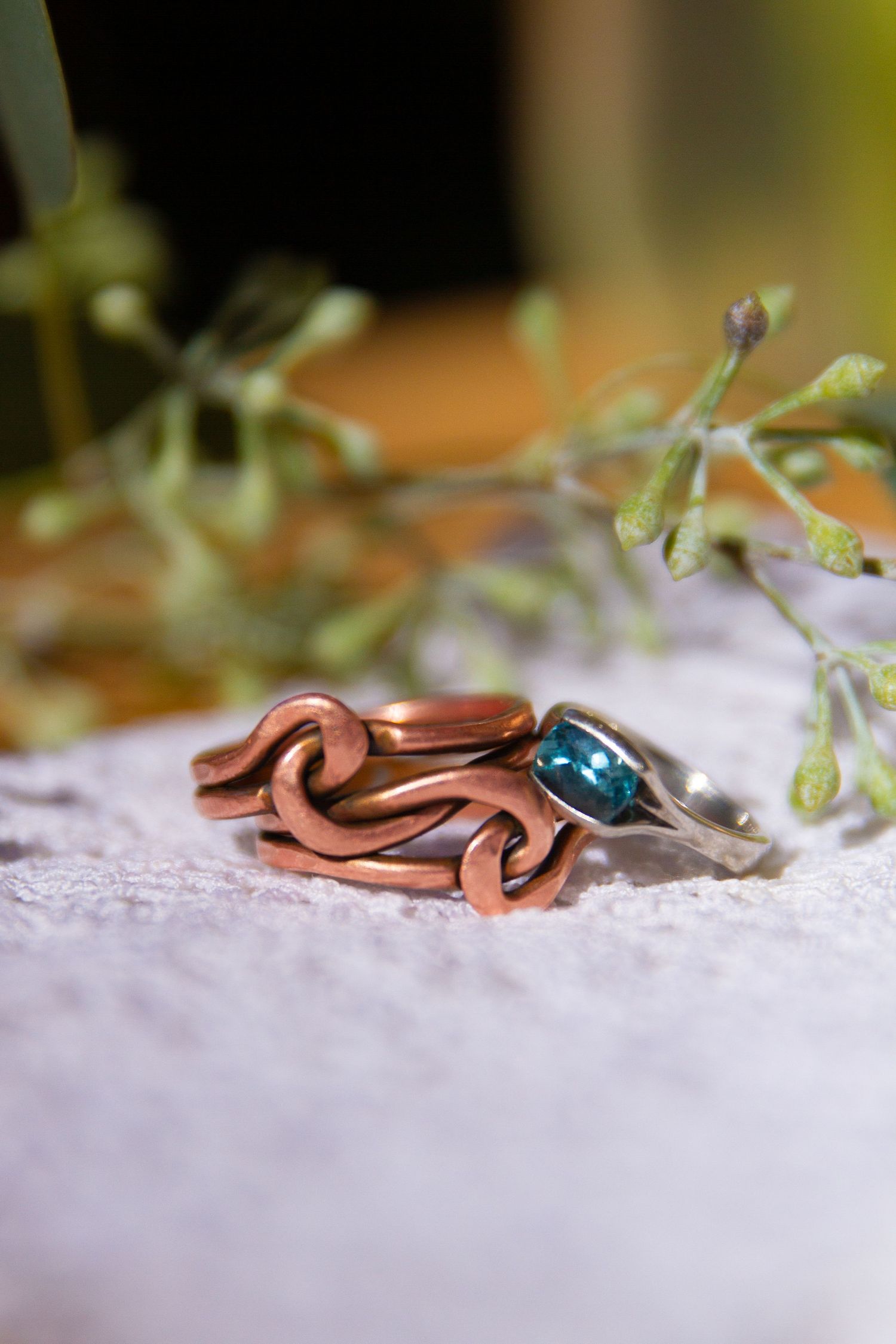 A pair of wedding rings with greenery in the background.a
